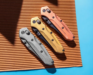 Custom Benchmade 945 knives with titanium, brass and copper scales.